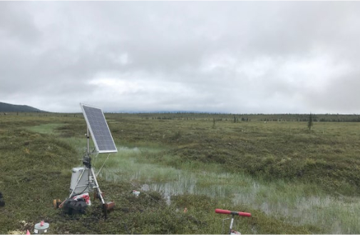 Grassy field with solar panel and scientific equipment